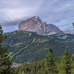 Foto 1: Masív Sassolunga (Langkofel) týčiaci sa nad zalesnenými svahmi Val Gardena, v údolí mestečko Selva di Val Gardena.