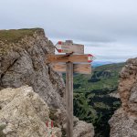 Foto 11: Rázcestník na skalnom hrebeni ukazujúci k chate Rifugio Stevia aj k vrcholu Col de la Pieres (1 h), v pozadí zelené doliny.