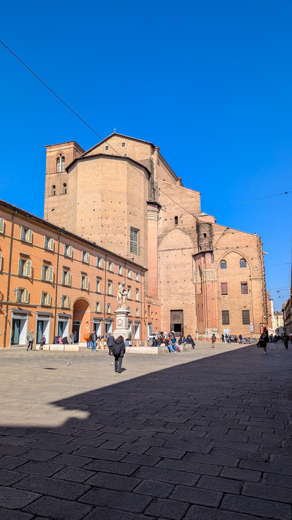Pohľad na Piazza Galvani so sochou Luigiho Galvaniho pred zadnou časťou Baziliky sv. Petrona. Luigi Galvani bol významný vedec a objaviteľ bioelektriny.