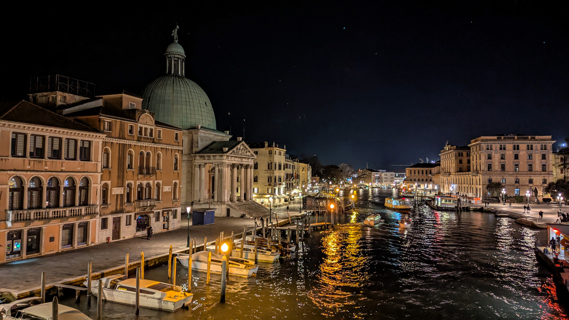 Nočný pohľad na budovu Chiesa di San Simeon Piccolo a Grand Canal v Benátkach, osvetlený reflektormi.
        