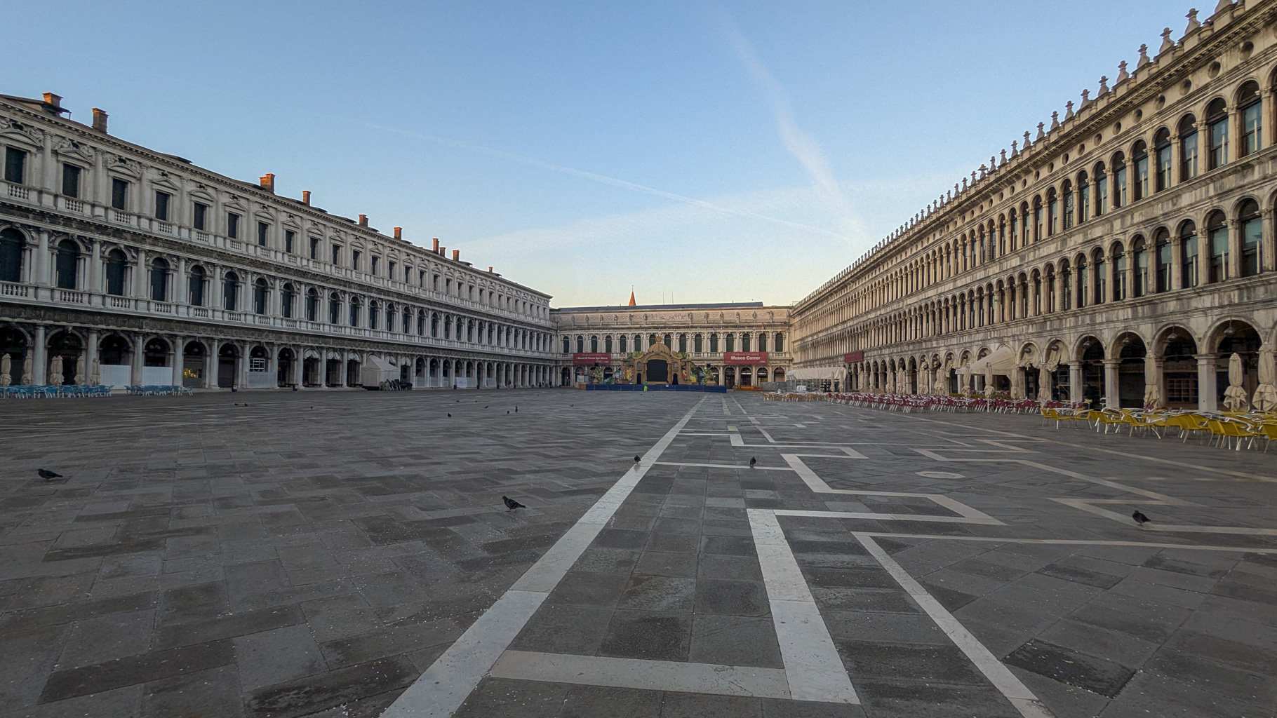 Prázdne ranné námestie Piazza San Marco pred začiatkom každodenného ruchu v Benátkach, zachytené v
            pokojnej atmosfére.
        